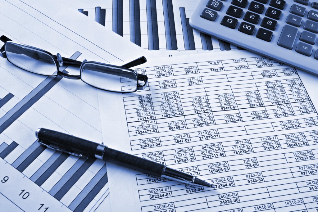 Financial advice concept. Glasses, a pen and a calculator lie on top of several financial services reports.