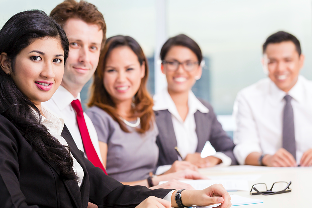 A group of male and female students sitting around a table at a financial services training course