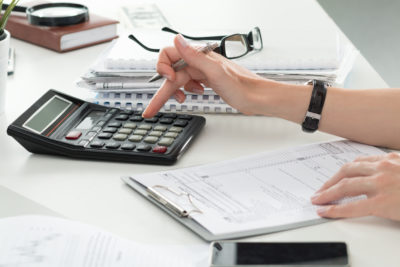 A financial adviser's hands are seen using a calculator to check through mortgage application paperwork.