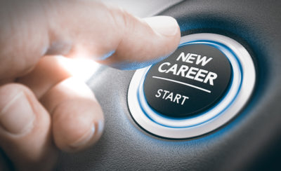 Training concept. Close up of a man's thumb hovering over an illuminated button showing the words 'New Career' and 'Start'.