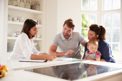 A Financial Advisor giving advice to a couple with their baby around a table and looking at documents