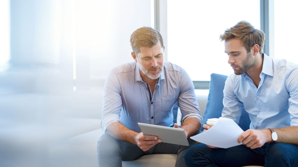 Two mens in workwear look over documents