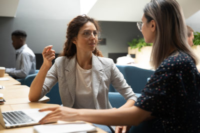 Business women talk at a desk together