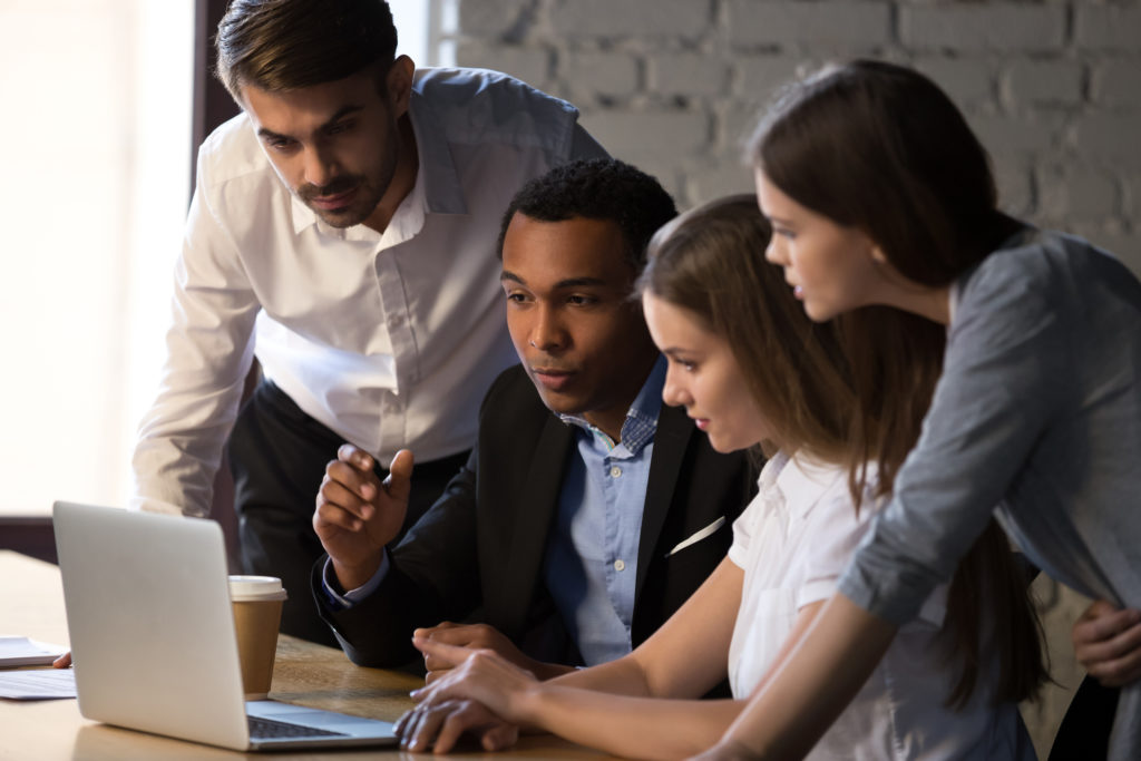 A group of keen financial apprentices gathered around a laptop.