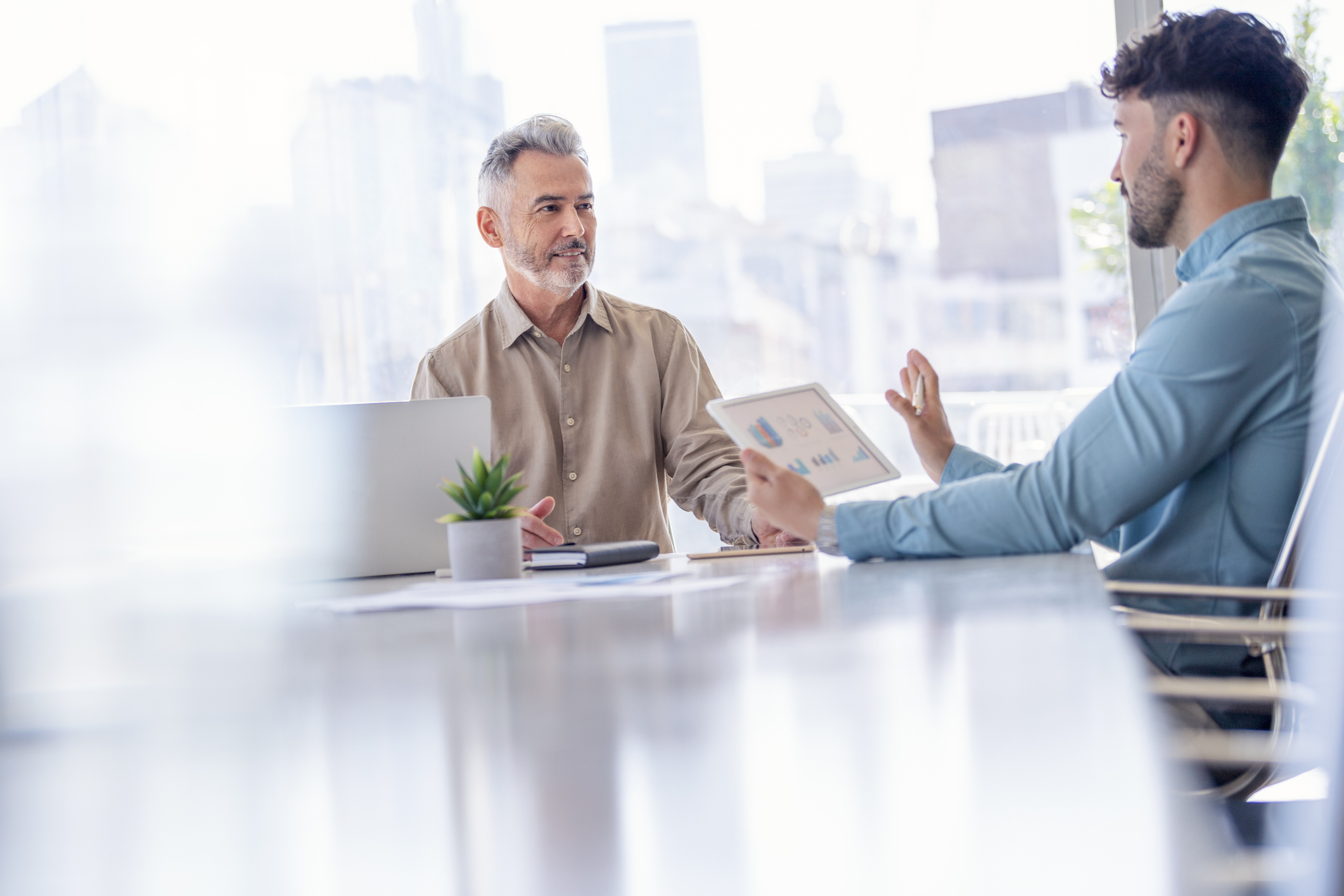 A financial adviser showing his client data on a digital tablet.