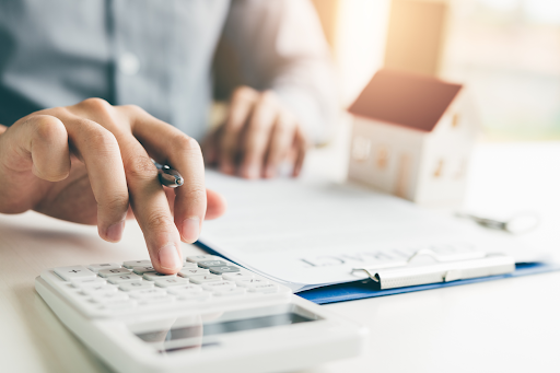 A mortgage adviser using a calculator while filling in paperwork for a client.