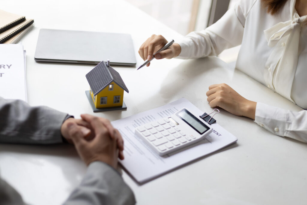 A mortgage adviser sits with a client in front of a calculator and paperwork.