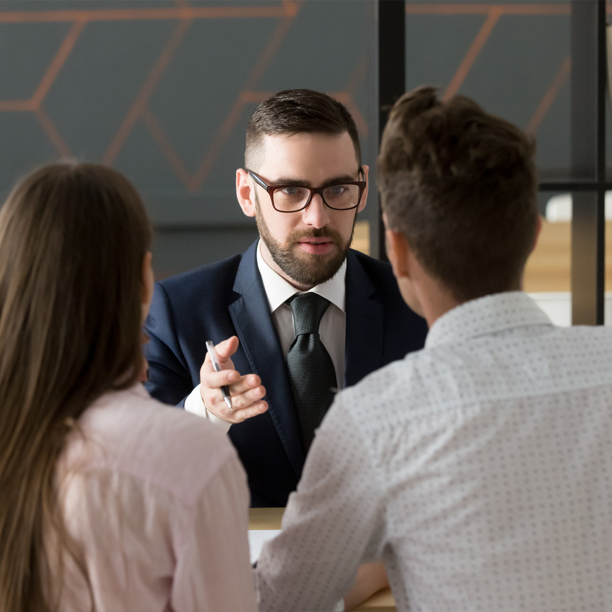 Young professional wearing a suit talking to two clients.