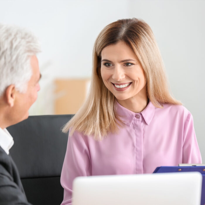 Smiling woman in conversation with an older gentleman wearing a suit.